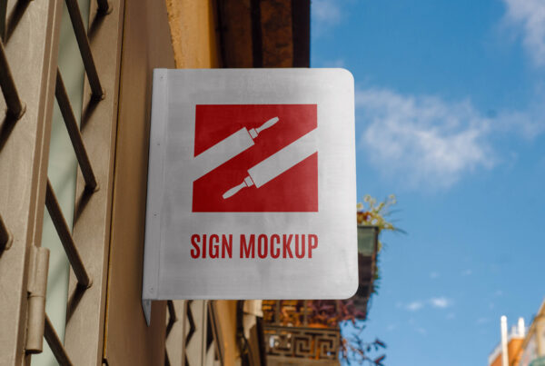 Front view, Hanging Metal Sign Mockup attached to building against sky view.