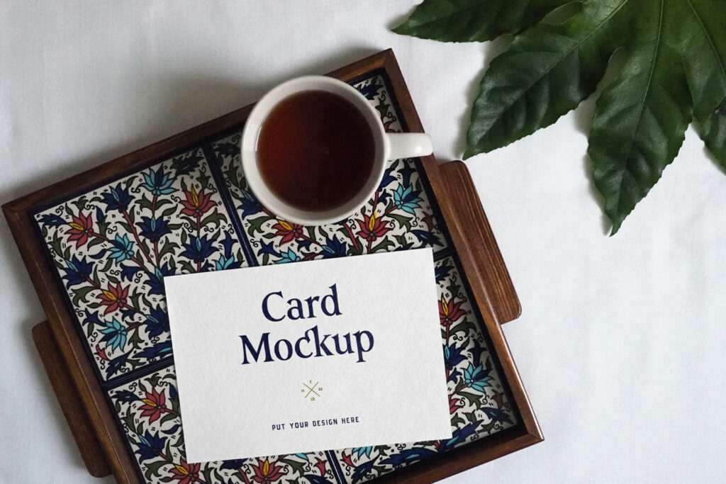 One Card PSD Mockup, it lies on a tray with colorful patterns next to a cup of coffee.