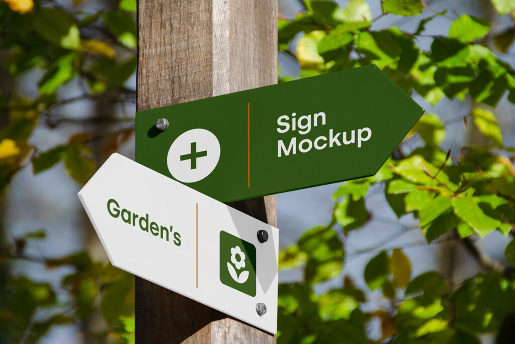 Wayfinding & Signage PSD Mockup attached to a wooden pole against the backdrop of gardens.