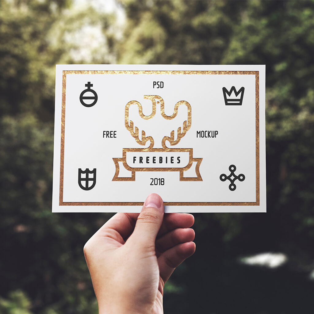 Men hand Holding Blank Card Mockup against the background of greenery.