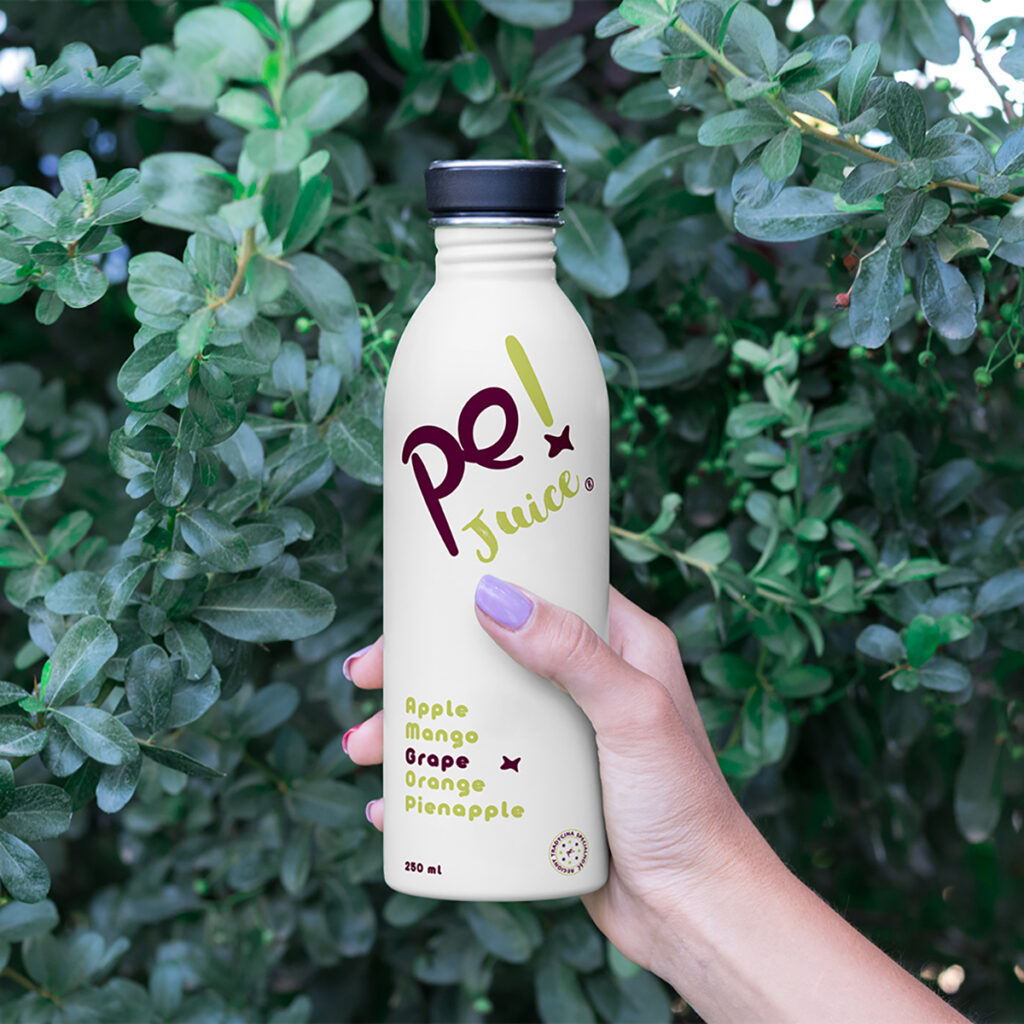 Women Hand Holding Bottle Mockup against the background of greenery.