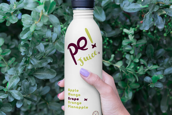 Women Hand Holding Bottle Mockup against the background of greenery.
