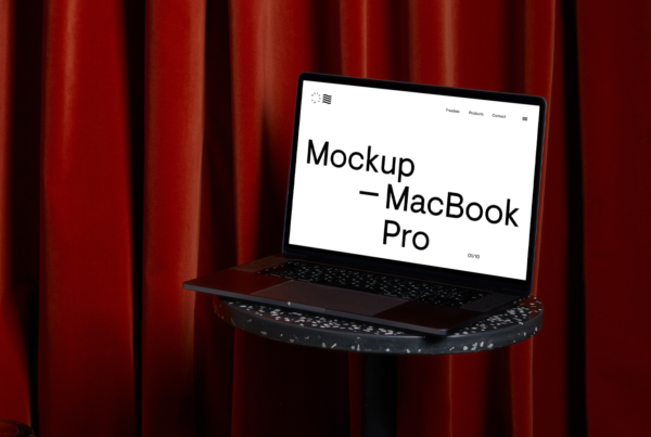 Open MacBook Pro Mockup on the black marble small table on with red curtain behind.