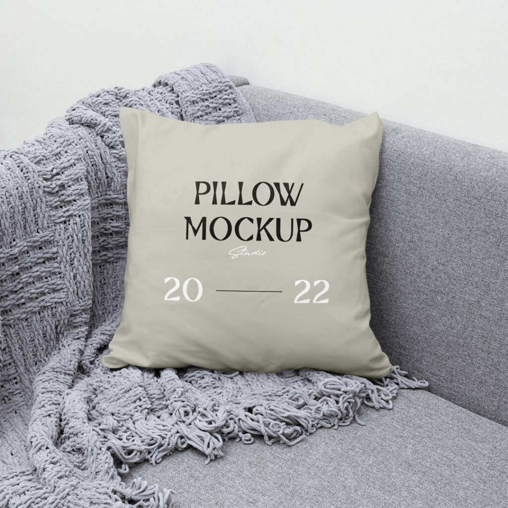 Front view Pillow Mockup lies on gray couch with gray blanket.