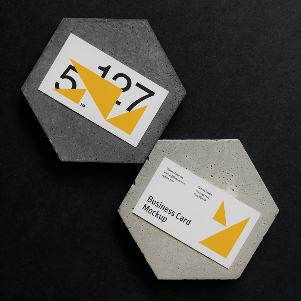 Two Business Cards on a Concrete Mockup form lies on the black floor.