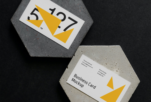 Two Business Cards on a Concrete Mockup form lies on the black floor.