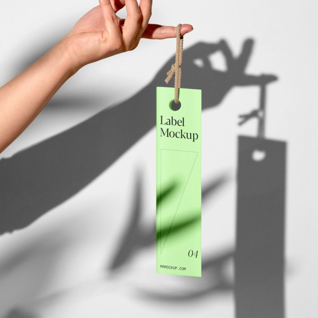 The label mockup hangs from hand in front of the wall.