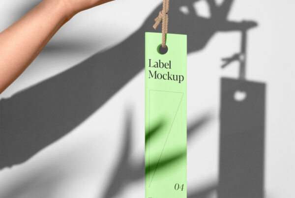 The label mockup hangs from hand in front of the wall.