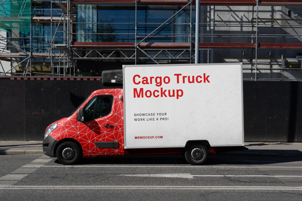 A cargo truck mockup stands on the road near the construction site of a new building.