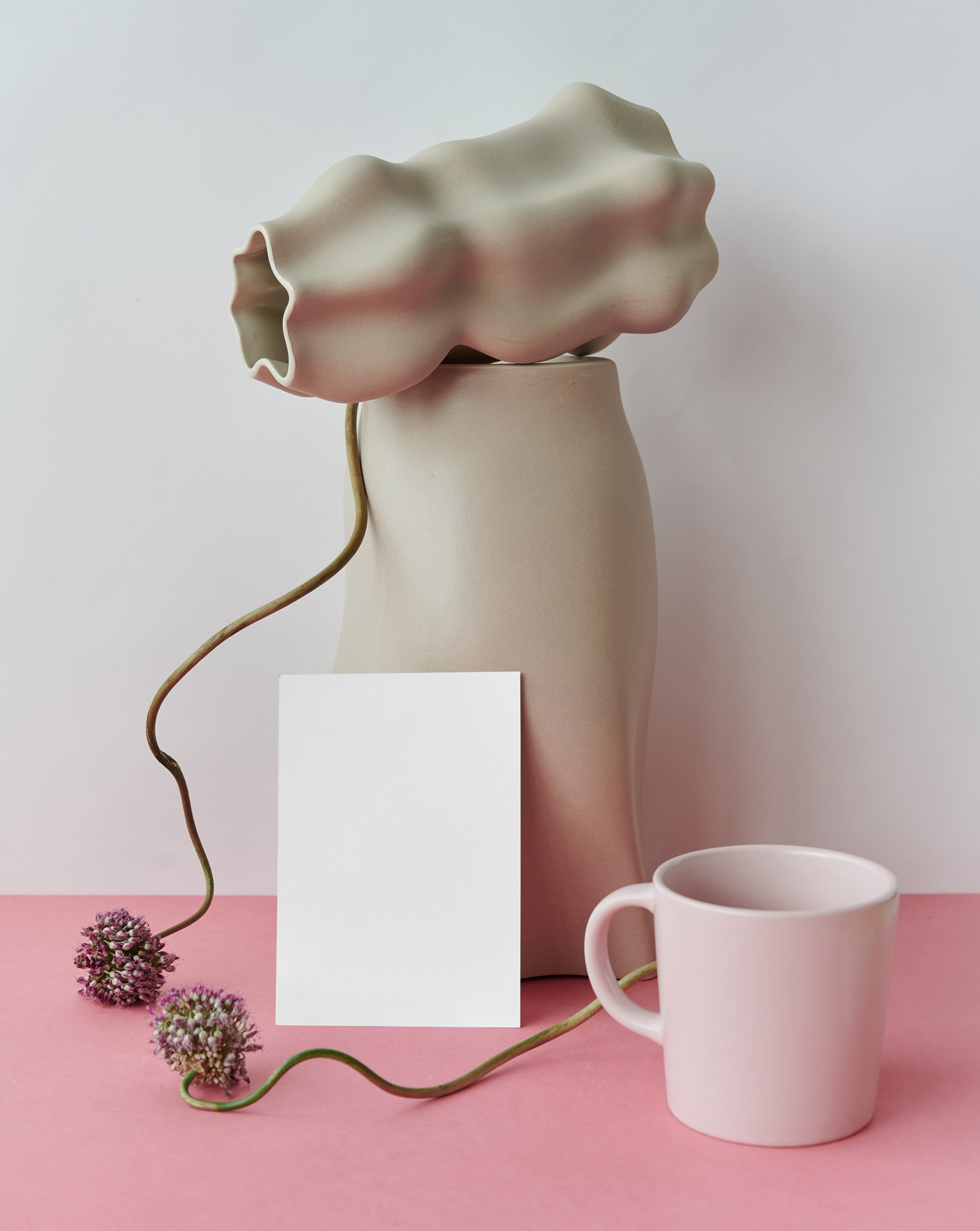 The blank card mockup is placed on the table with decoration, vases and mug seen from the front.