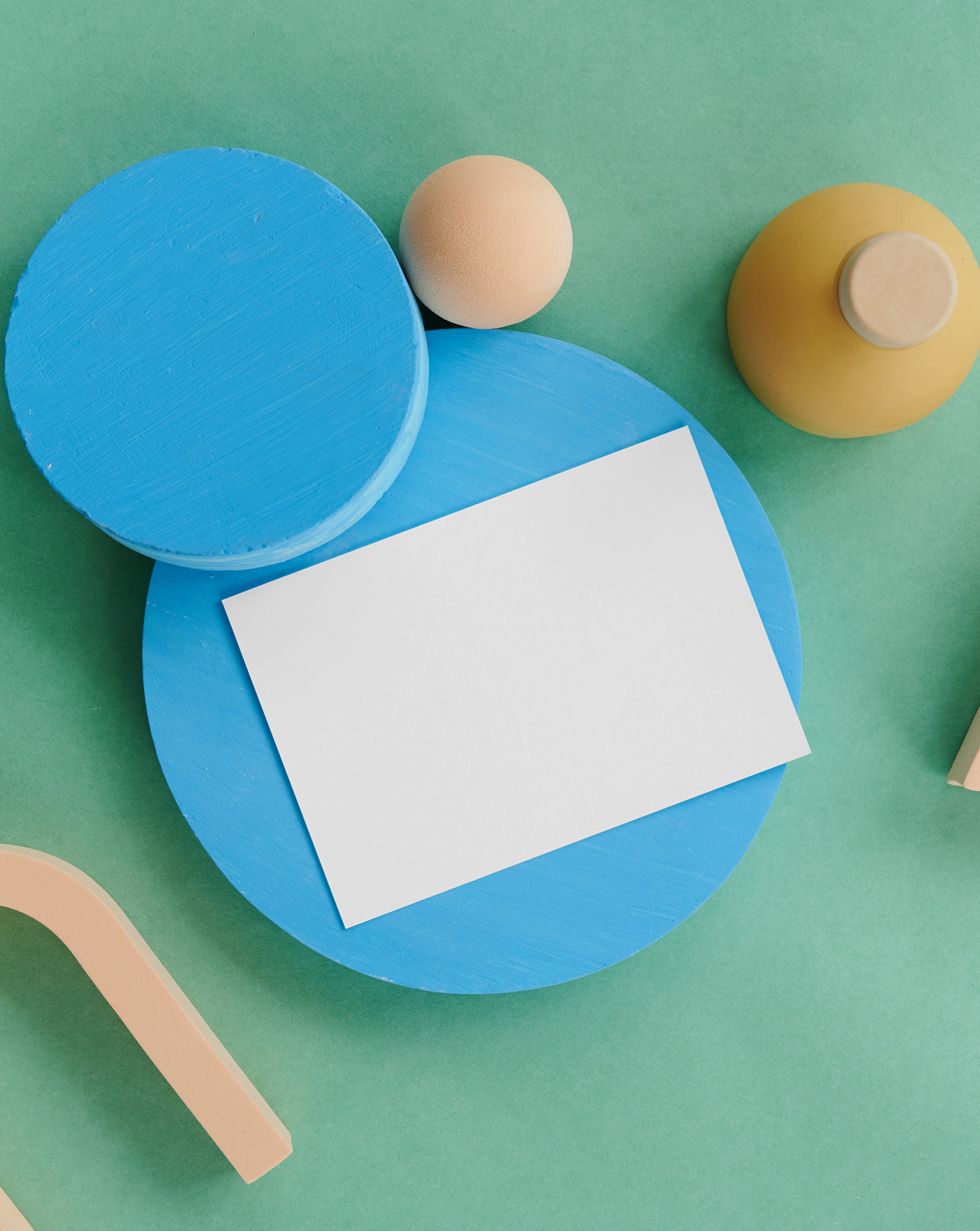 The white card mockup is placed on a blue circle block, seen from above.