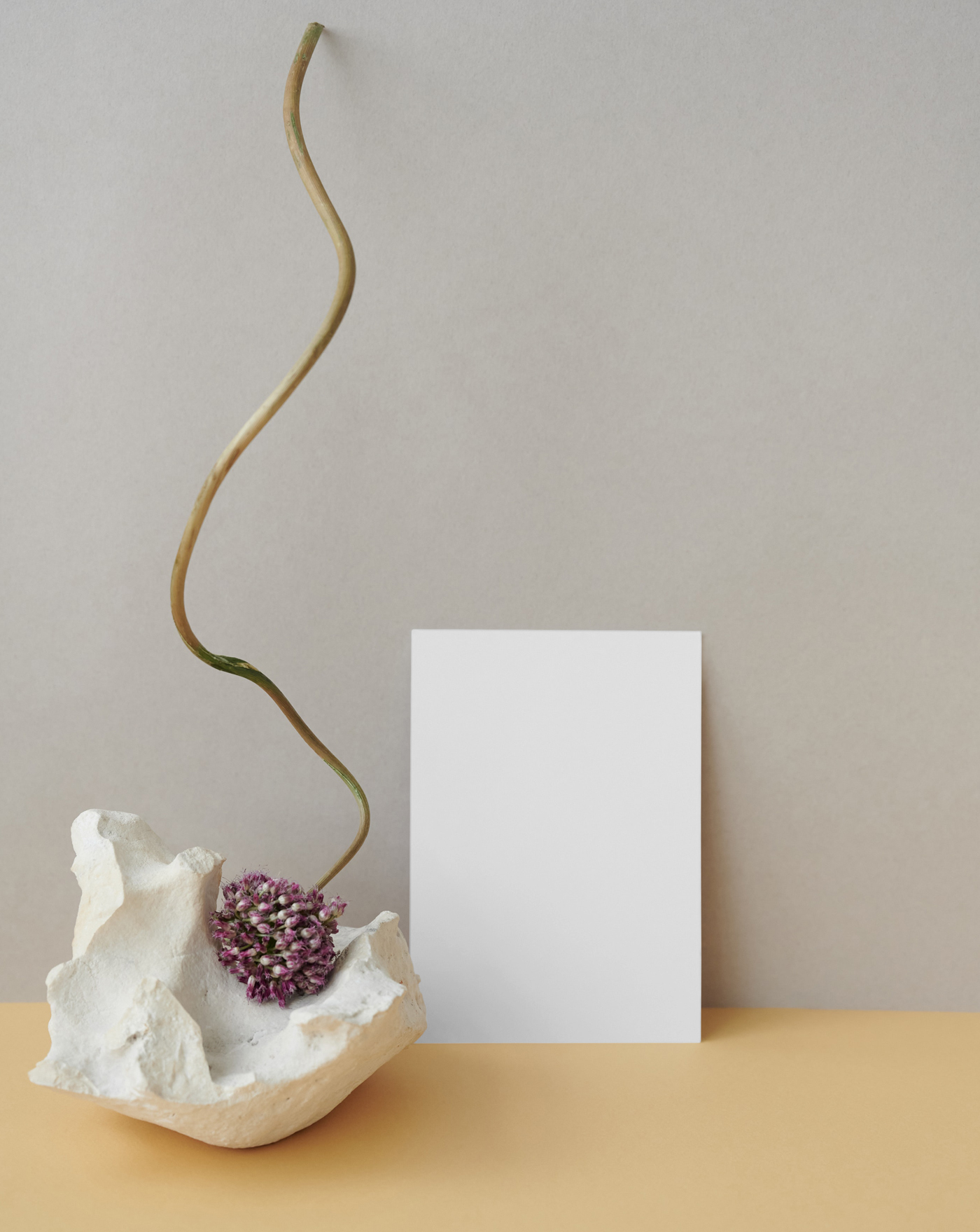 The white card mockup is placed on the desk with stone and flower, seen from the front.