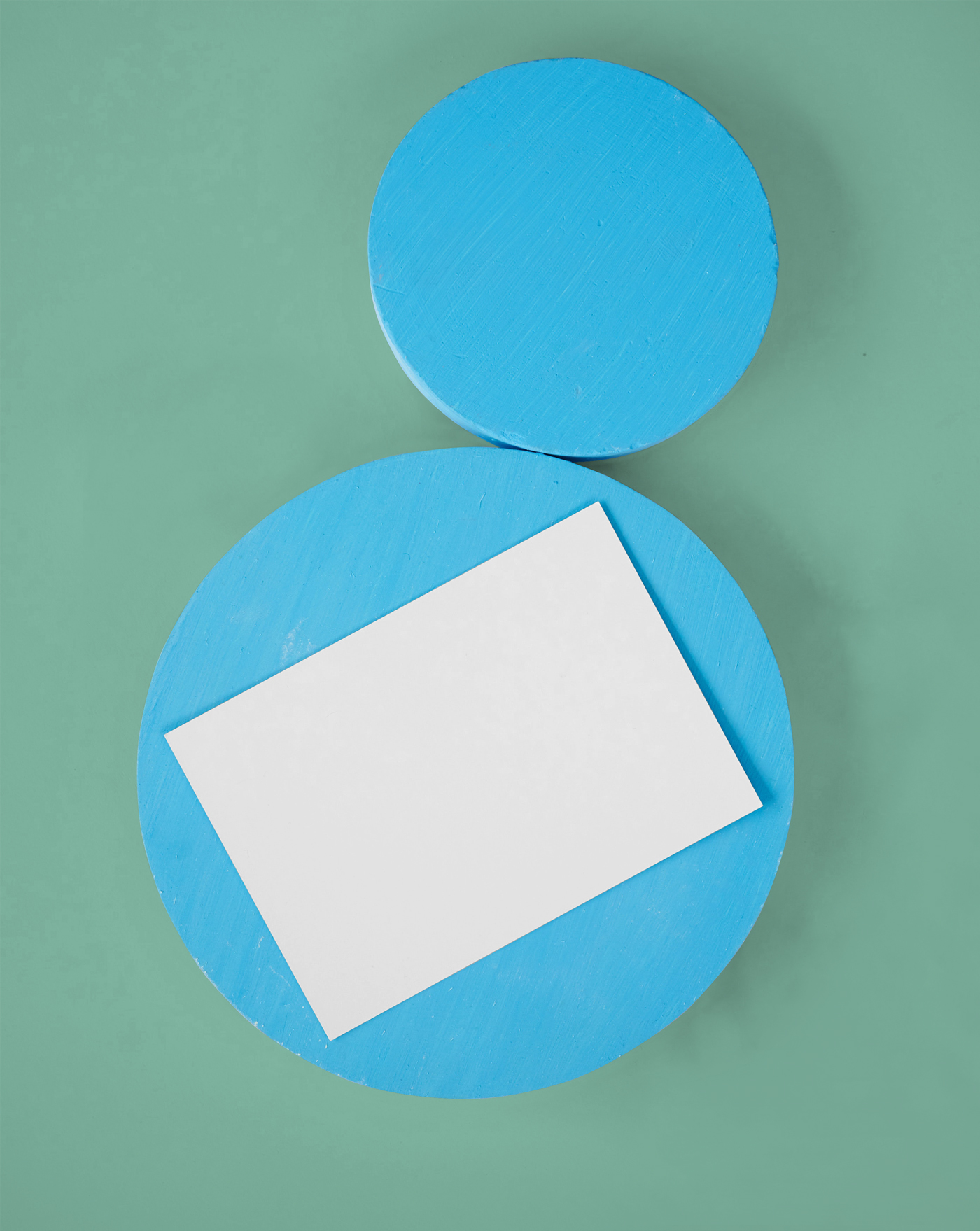 The white card mockup is placed on a blue circle block, seen from above.