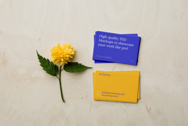 Business cards lying on plywood next to a yellow flower