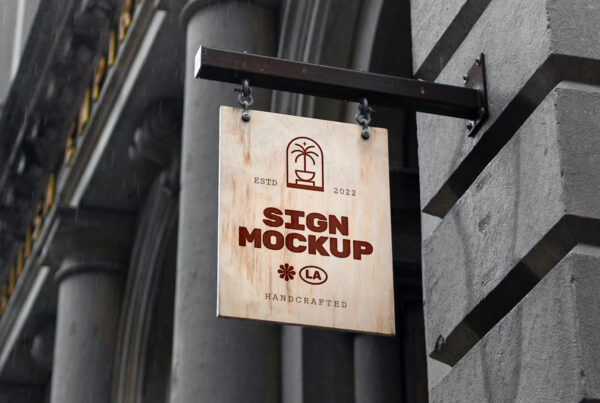 Wood sign hanging on chains on the black metal arm attached to building elevation i dark gray color.