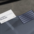 Two business cards laying on the blue glass from outdoor branding mockups.