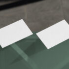 Two white business cards laying on the glass from outdoor branding mockups.