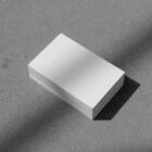 Stack of white business cards on the concrete floor from outdoor branding mockups.