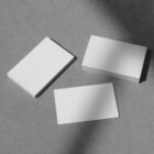 Three stacks of white business cards on the concrete floor from outdoor branding mockups.