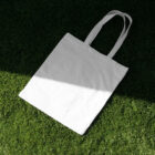 White canvas bag on the grass from outdoor branign mockups.
