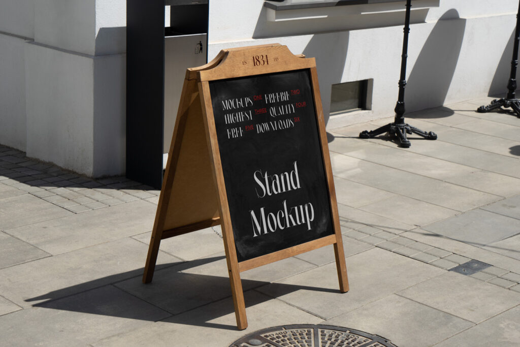 A Free Wooden Stand Mockup is standing on the sidewalk.