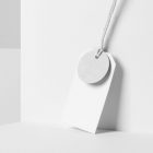 White circle label, and White rectangle Label Branding Mockup hooked on a white string, standing against the background of a white wall.