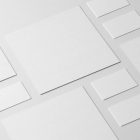 Seen from the above a set of White Branding Mockups, elements like Business Cards and Square Cards presented in an interesting composition laying on the white floor.