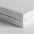 Seen from the front, close-up of the corners of White Hardcover Book Branding Mockups laying on the white textured floor.