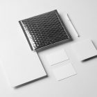 Seen from the above, a set of White Branding Mockups elements like business cards, envelopes, pen and company paper laying on the white floor.