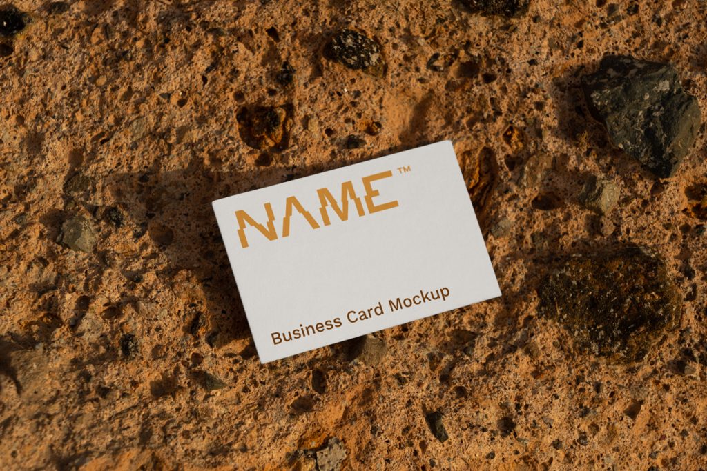 Free Business Card Mockup seen from above laying on the orange stone.
