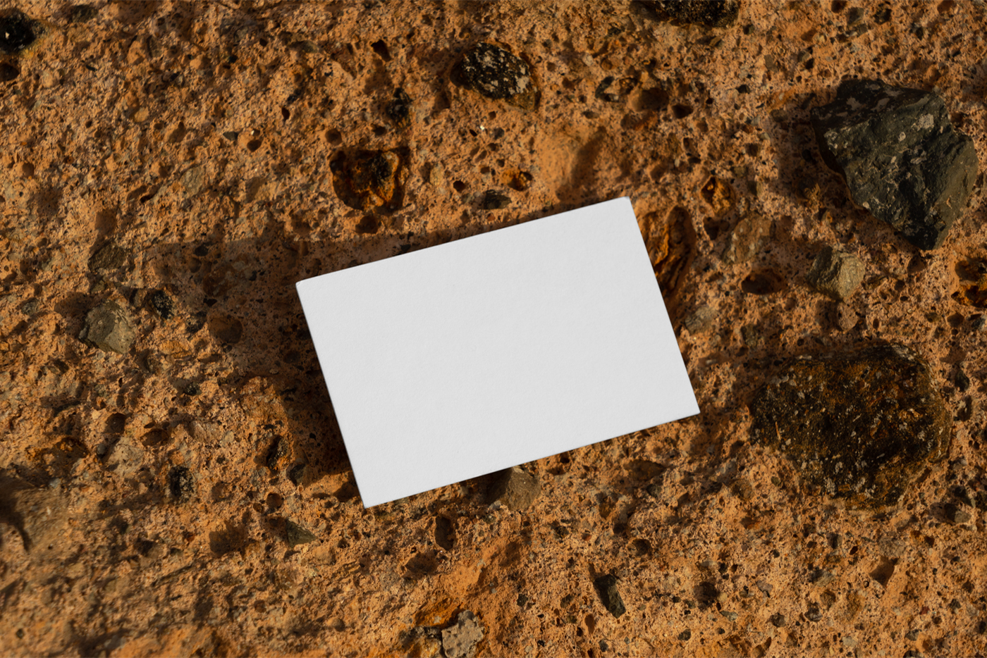 White Free Business Card Mockup seen from above laying on the orange stone.