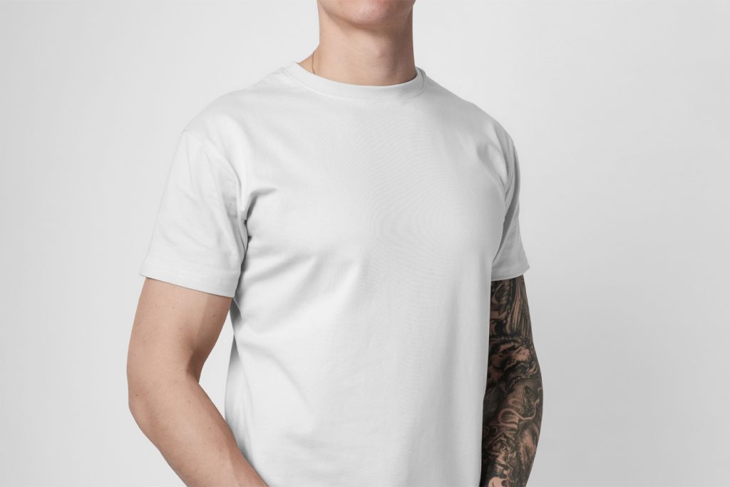 Standing man wearing White Free Front T-Shirt Mockup on the white wall background.