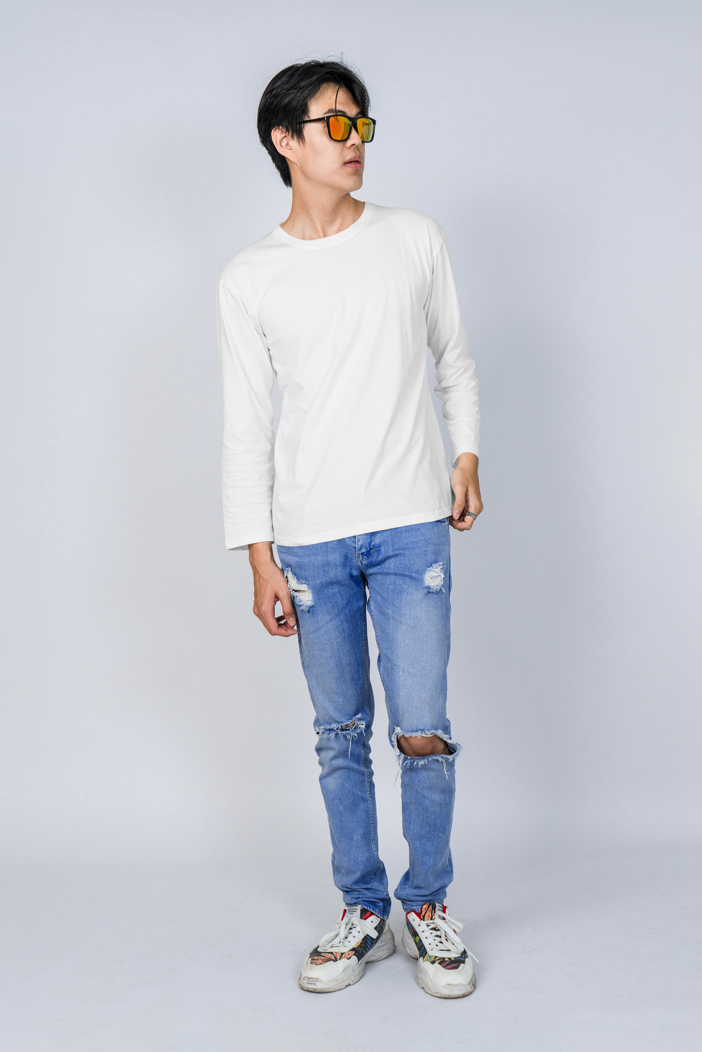 Man standing and wearing White Free Longsleave on Men in Studio Mockup against gray wall background.