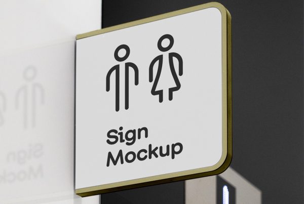 Free Modern Sign Mockup seen from the front is attached to the white wall with golden frame against elevators.