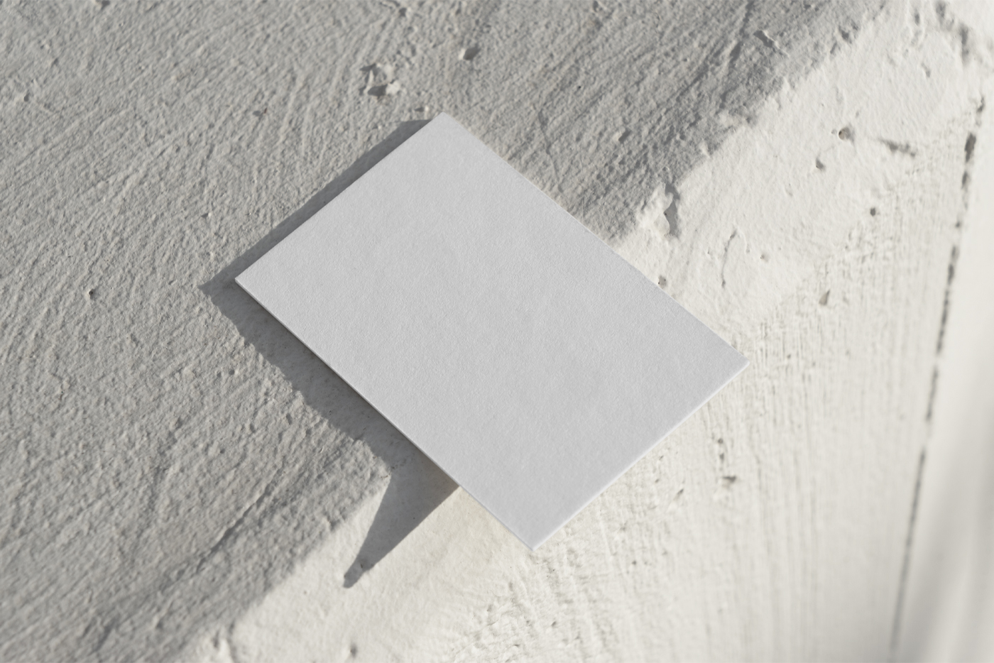 Free White Outdoor Business Card Mockup seen from above laying on the cream color concrete.