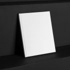 The White Hardcover Book Branding Mockups Kit, seen from the front, is standing on the black wooden stairs.