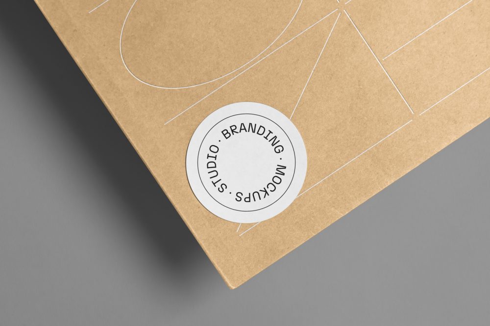 Big zoom on the circle Sticker Branding Mockup glued to craft card against a gray background.