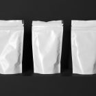 Three Blank Coffee Bags Branding Mockups Kit, seen from the front, is standing located on the black wooden stairs.