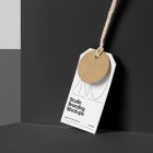 Craft circle label, and White rectangle Label Branding Mockup hooked on a craft string standing against the background of a black wall.