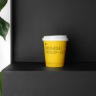Coffee Cup Branding Mockup with yellow design scene seen from front standing on the black wooden stairs.