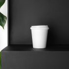 White Coffee Cup Branding Mockup scene seen from front standing on the black wooden stairs.