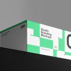 Viewed from below at an angle, a Box Branding Mockup with a modern green design is standing on a black box against a gray background.
