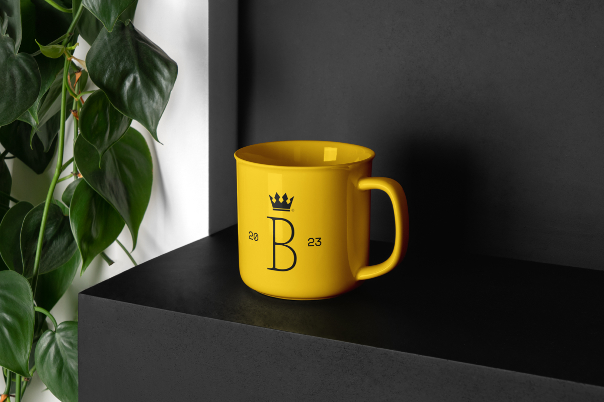 Metal Mug Branding Mockups Kit with a yellow design seen from above is standing on the black wooden stairs.