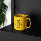 Metal Mug Branding Mockups Kit with a yellow design seen from above is standing on the black wooden stairs.