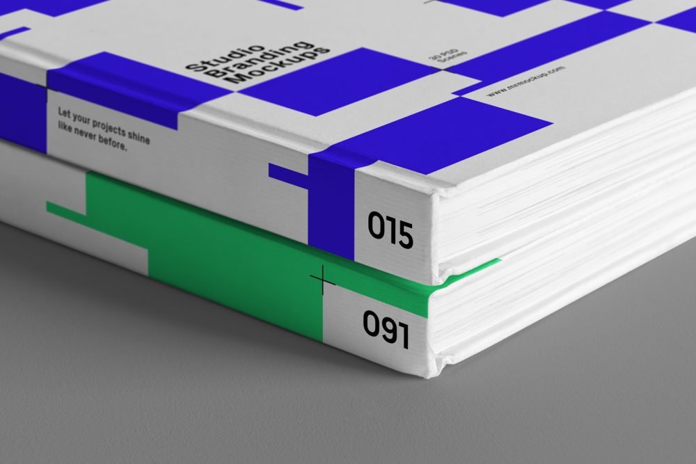 Seen from the front, close-up of the corners of a Hardcover Book Branding Mockups with blue and green modern design laying on the gray textured floor.