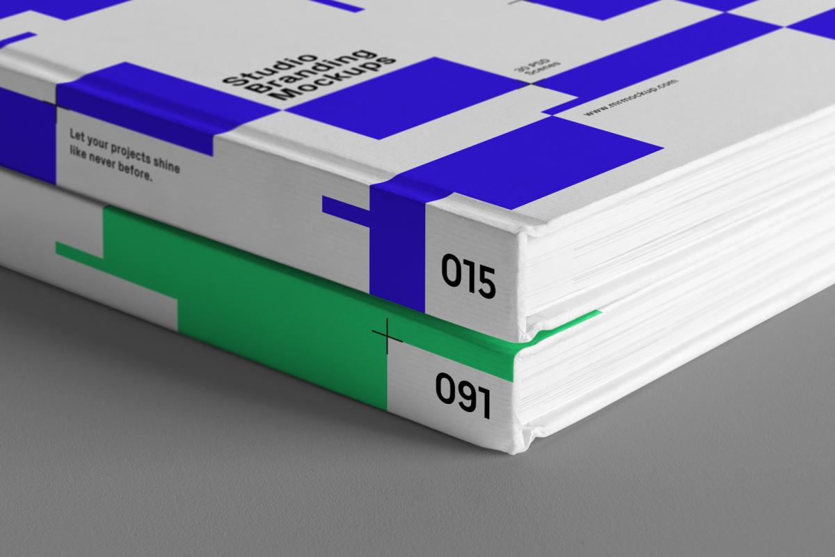 Seen from the front, close-up of the corners of a Hardcover Book Branding Mockups with blue and green modern design laying on the gray textured floor.