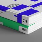 Seen from the front, close-up of the corners of a Hardcover Book Branding Mockups with blue and green modern design laying on the gray textured floor.