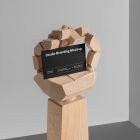 Huge Wood Hand holding a black Business Card Branding Mockup seen from the front on a gray background.