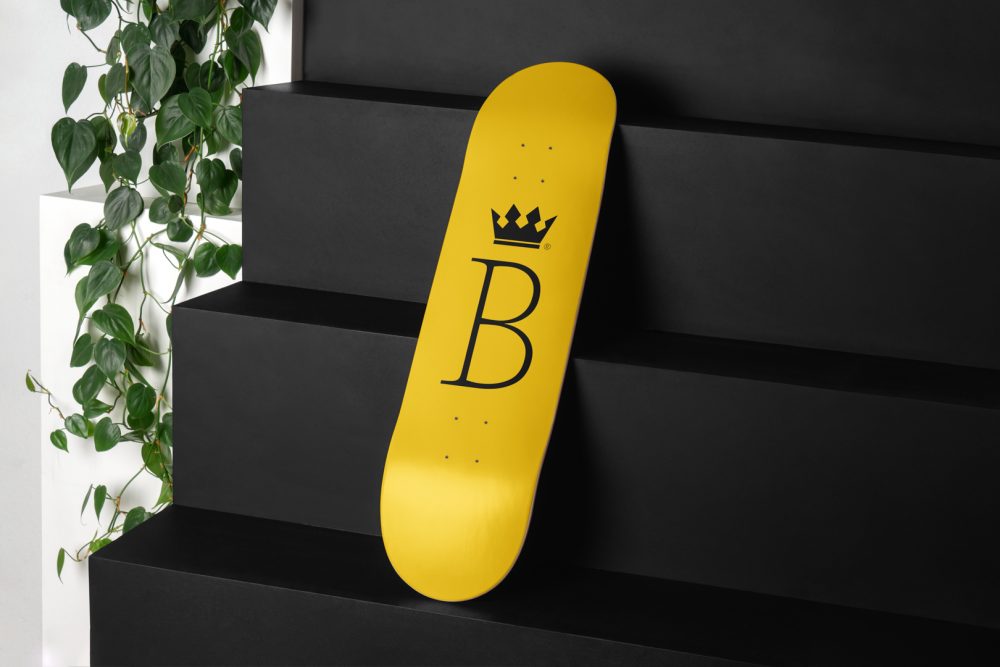 Skateboard Deck Branding Mockups Kit with yellow design seen from above and located on the black wooden stairs.