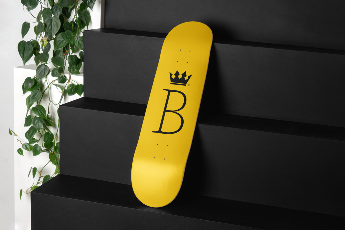 Skateboard Deck Branding Mockups Kit with yellow design seen from above and located on the black wooden stairs.